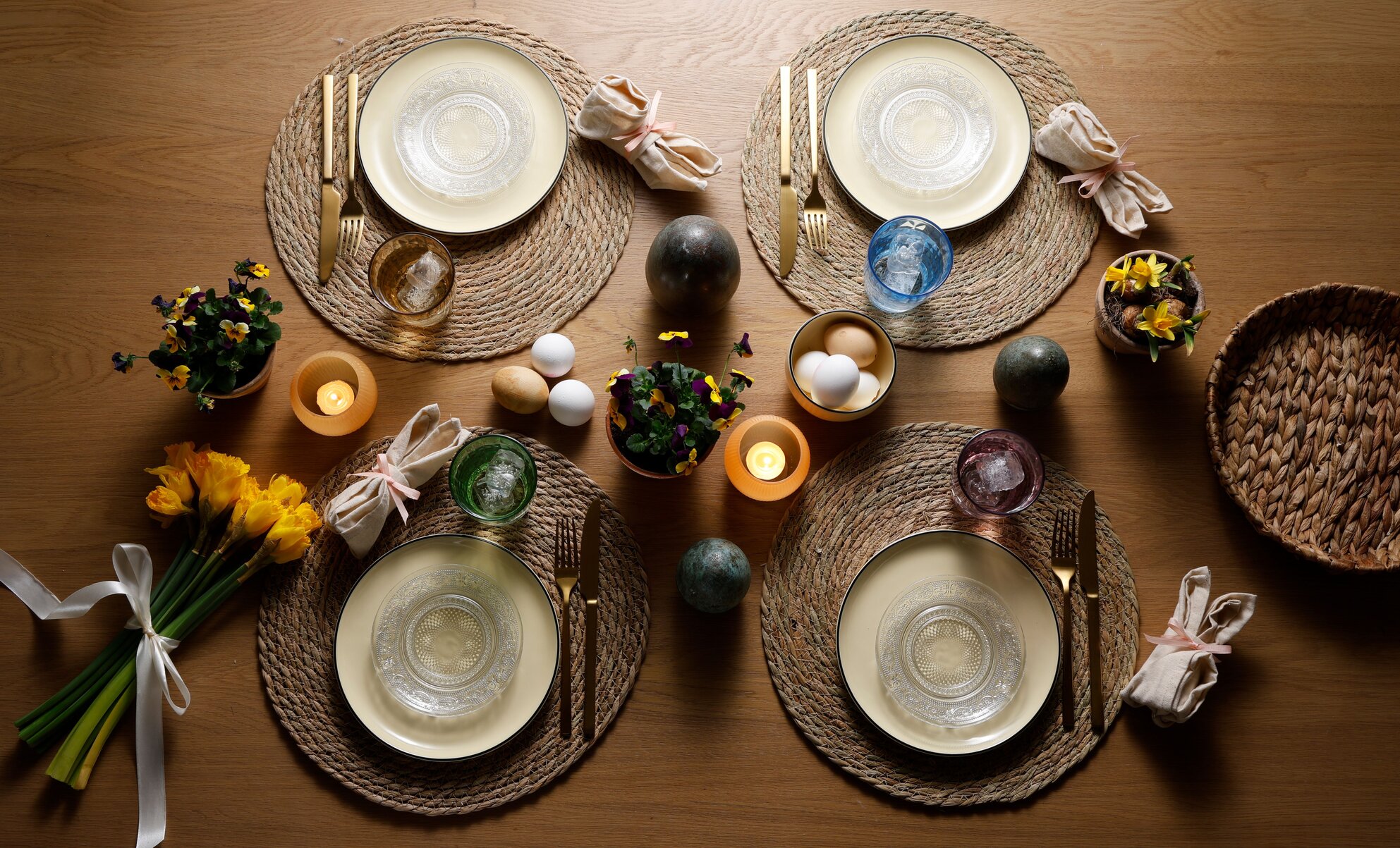 Havefest i eftermiddagsolen med blomster, lyskæder i træerne, og gæster der sidder rundt om borde i haven.