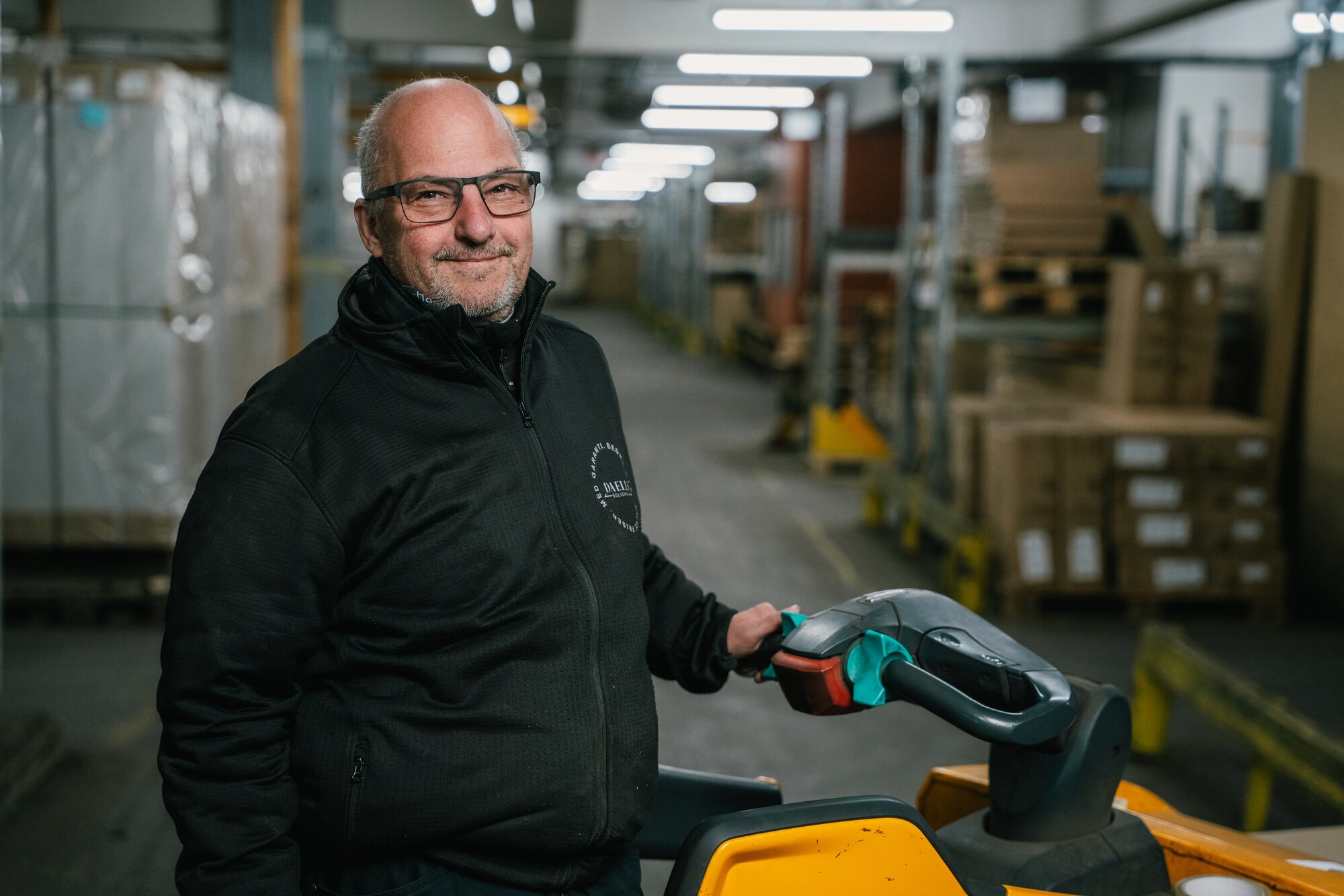 Mandlig lagermedarbejder i Daells Bolighus står på en truck på lageret.