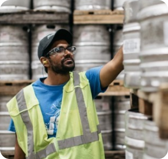 Man standing in front of a pallet of metal beer barrells 