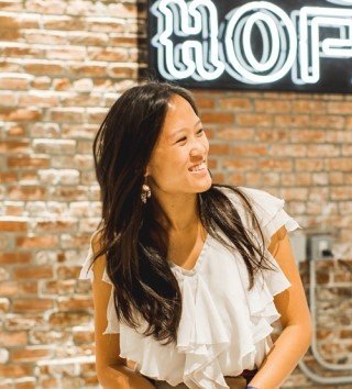 Woman standing in front of a neon sign on a brick wall