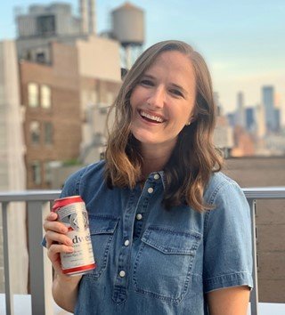 Woman standing on a rooftop with a can of budweiser in hand