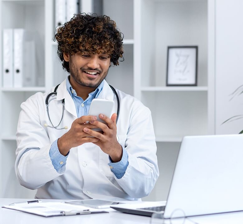 A doctor using his phone and laptop for telemedicine