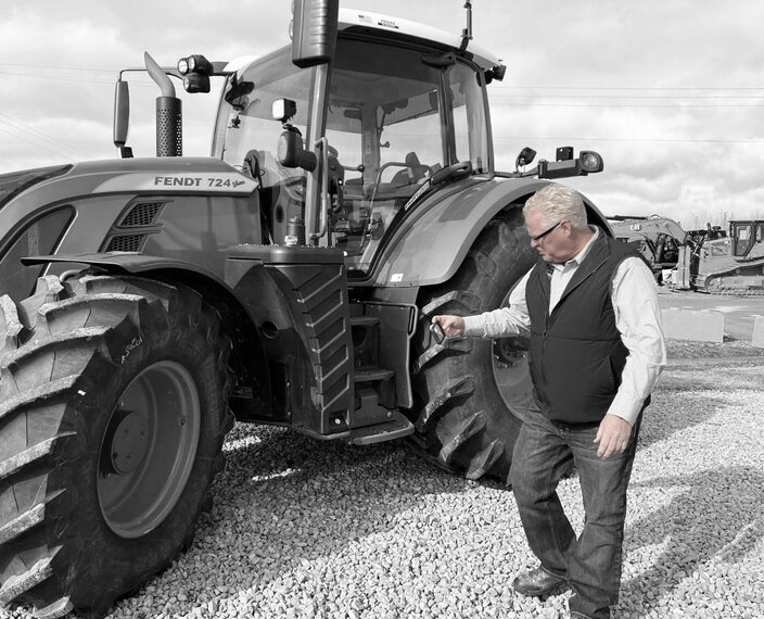 man taking photo of tractor tires with mobile phone