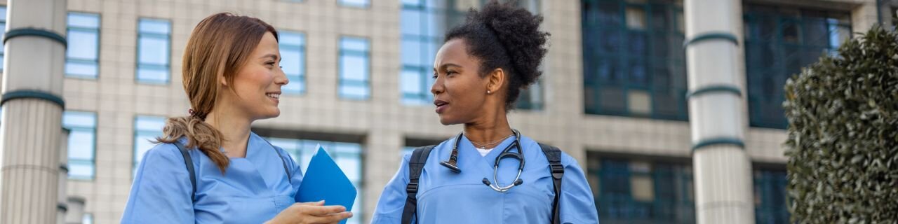 A professional hospital HR manager and a new healthcare employee reviewing digital onboarding documents on a tablet in a bright, modern medical office.
