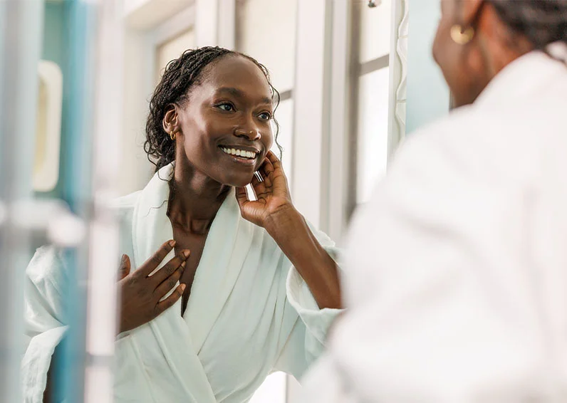 Woman in the gym in a green workout outfit grabbing weights and looking in the mirror