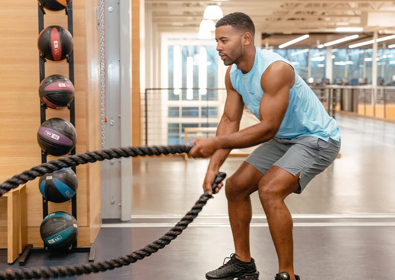 Man doing rope exercises in the gym with newfound confidence as a result of his men's brazilian laser hair removal