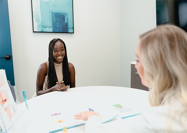 A woman wearing a tan top speaks with a Milan Laser Clinic Manager in a consultation room in an image for a blog titled What To Expect During A Laser Hair Removal Session.