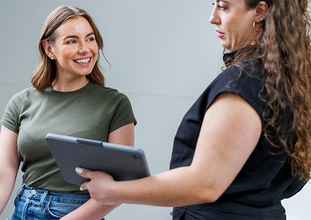 A woman wearing a green shirt chats with a Milan Laser Provider in a treatment room for a blog titled Laser Hair Removal Success Stories.