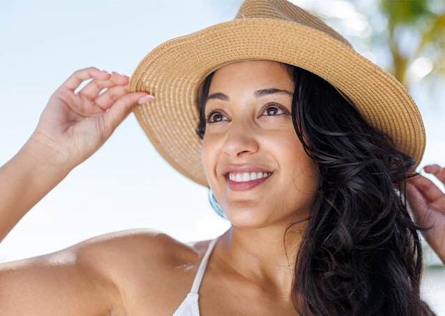 A woman in a purple swimsuit has a glowing smile, realizing there's a solution for women who don't have PCOS but have facial hair.