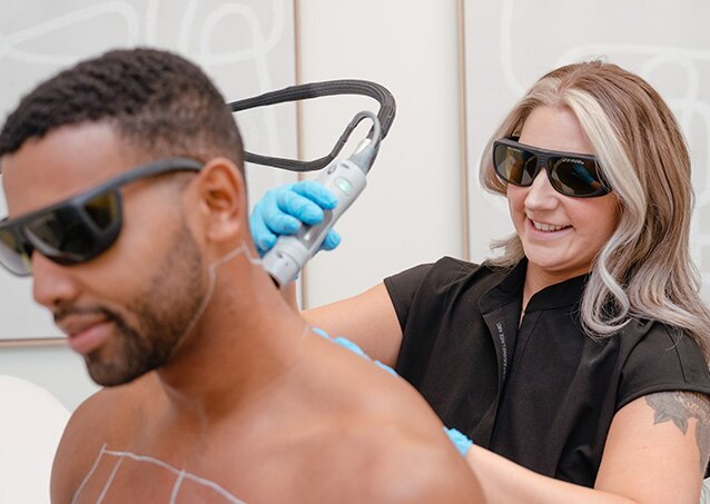 A Milan Laser Provider in black scrubs performs laser hair removal on a man wearing protective eyewear in an image for a blog titled Common Laser Hair Removal Concerns & How Milan Addresses Them.