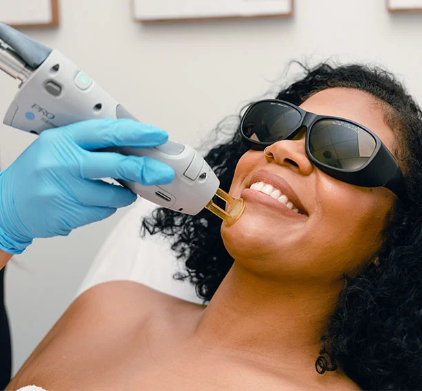 Smiling woman getting chin laser hair removal with black glasses on