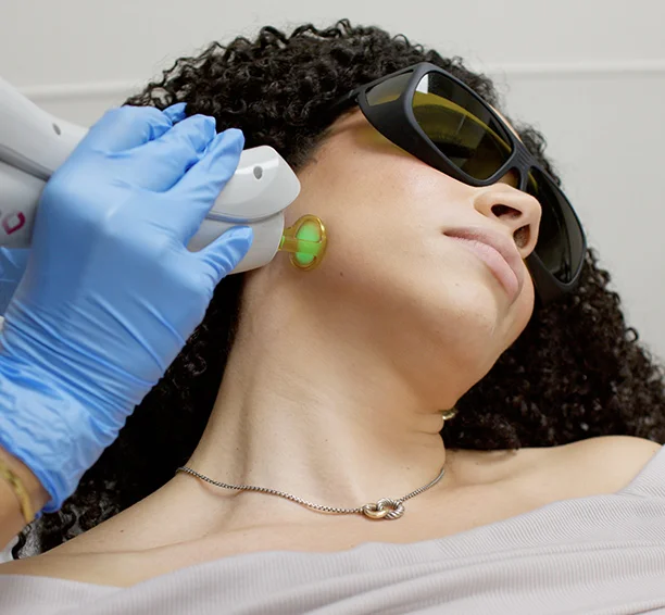 Guy getting the back of his neck laser hair removal treated by a tech in blue gloves