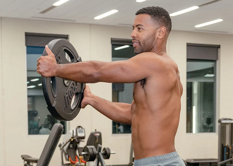 Guy doing an arm extension with a round black weight