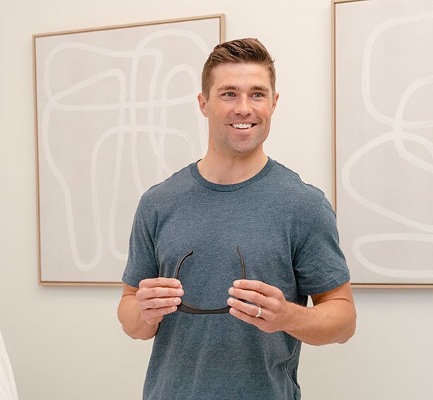 Man in a grey shirt holding sunglasses at his laser hair removal for men appointment
