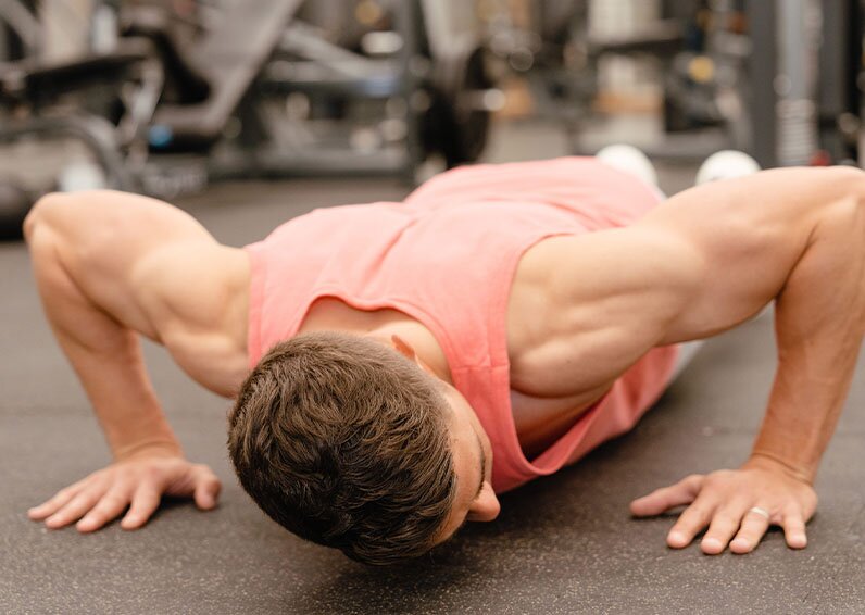 Man doing pushups in a gym and looking to his left