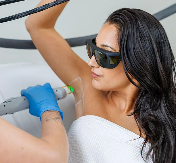 Woman in a white robe wearing sunglasses getting treated with laser hair removal on her underarms in a Milan Laser Hair Removal Clinic