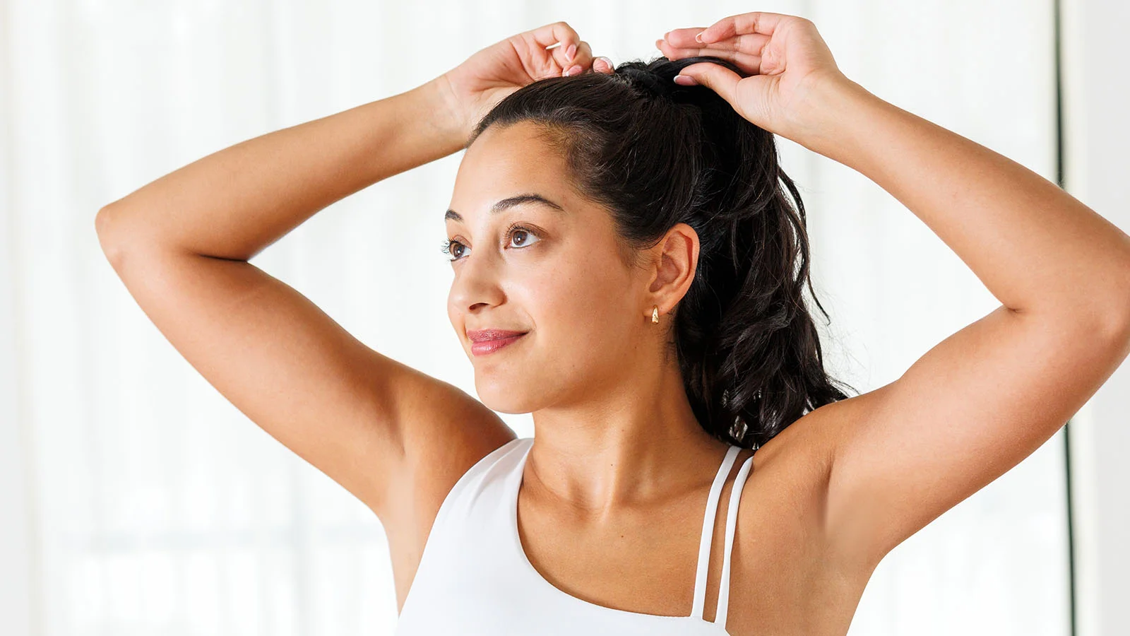 Pretty woman holding her arms above her head after getting underarm laser hair removal at a local Milan Laser clinic