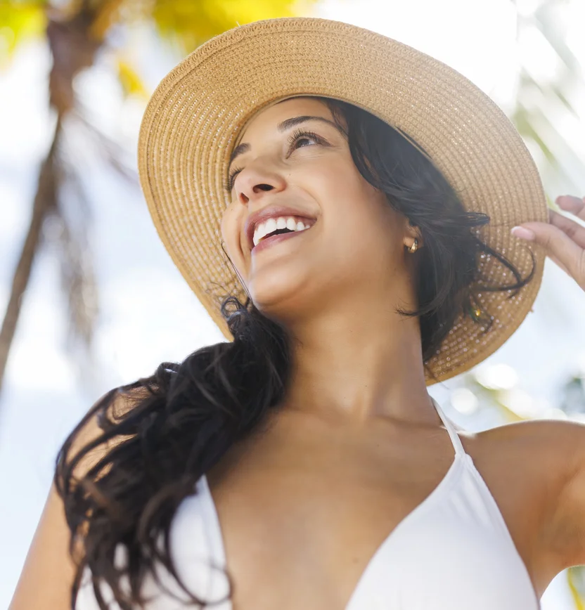 Woman in a tan hat looking up and to the right while the sun shines behind her