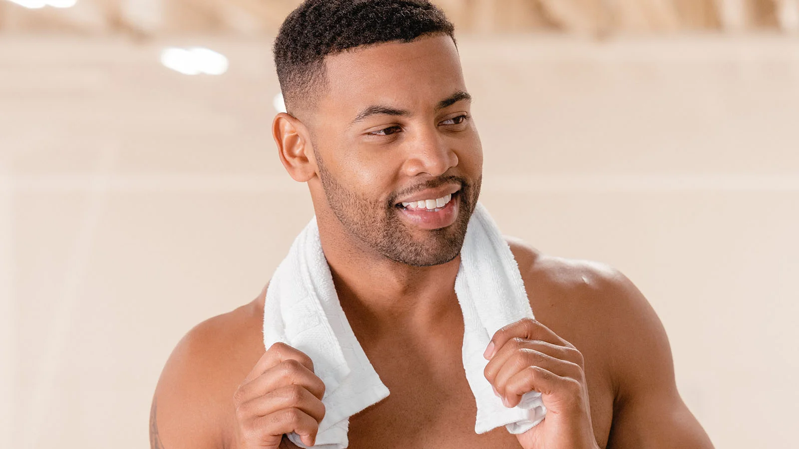 Man holding a towel over his shoulders and smiling in a gym after getting men's laser hair removal at a local Milan Laser clinic near him