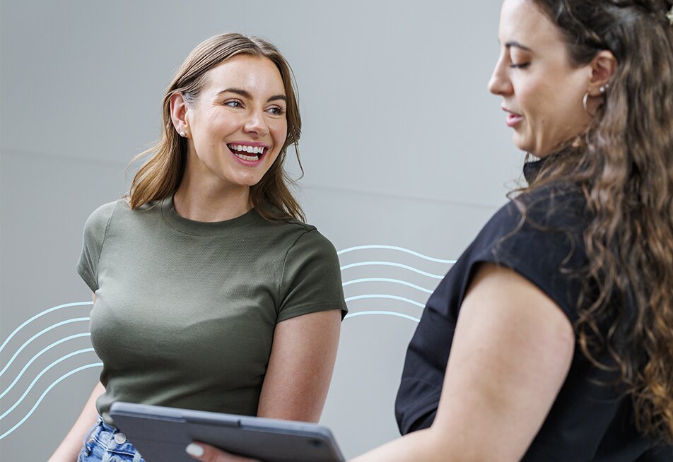 Woman in a dark green top smiling and looking to her left at someone at Milan Laser Hair Removal explaining the process to her