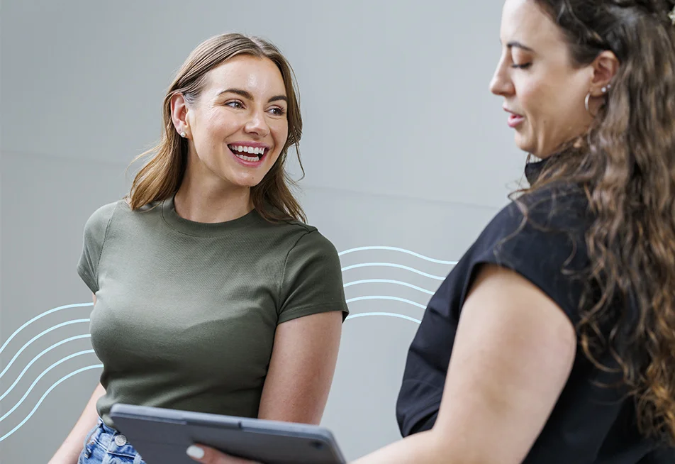 Woman in a dark green top smiling and looking to her left at someone at Milan Laser Hair Removal explaining the process to her