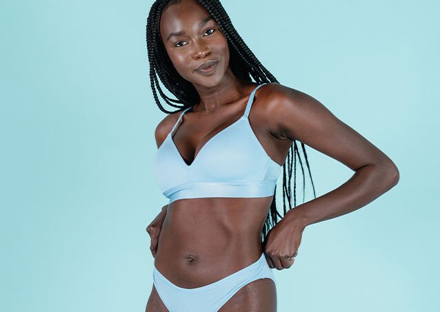 Woman in a baby blue bikini smiling and holding her hips