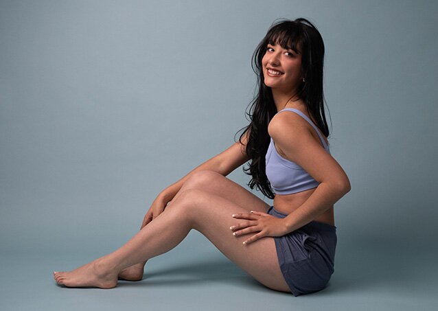 A woman wearing a purple top and dark shorts poses in an image for a blog titled The Best Time Of Year For Laser Hair Removal.