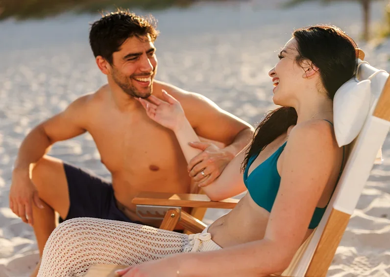 Man in the gym holding a towel over his shoulders with a blue wall in the background