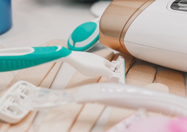 Close-up of razors and shampoo lying on sticks for a piece titled laser hair removal vs waxing