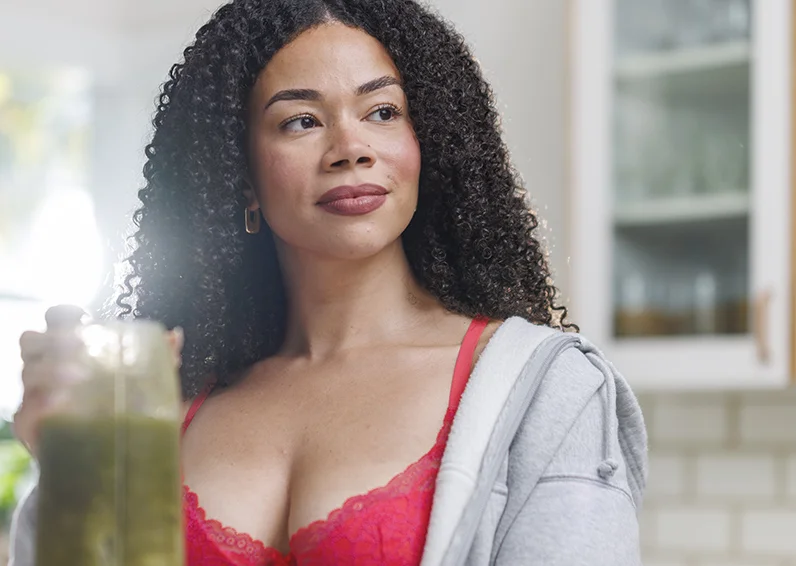 Woman in a red bra looking left and holding a smoothie