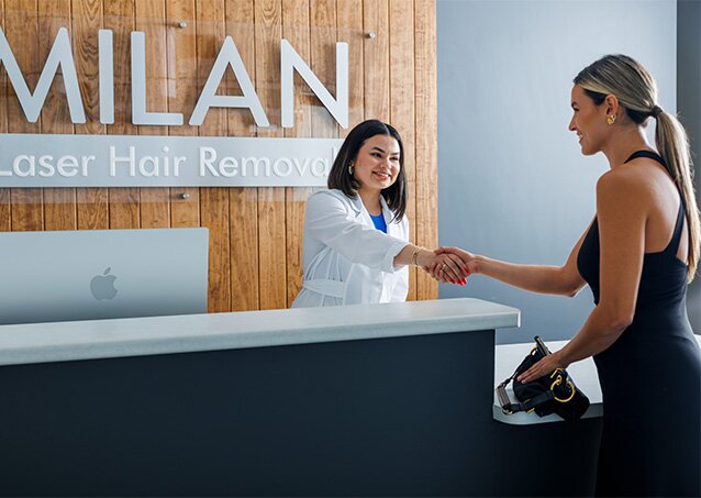 A woman wearing black workout clothes shakes hands with a Milan Laser Clinic Manager in an image for a blog titled Hair Removal for Busy Lifestyles: Why Laser Hair Removal Is the Low-Maintenance Solution.