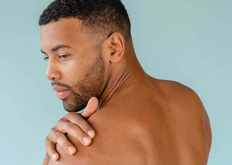 Man holding his shoulder and smiling because he just got neck laser hair removal