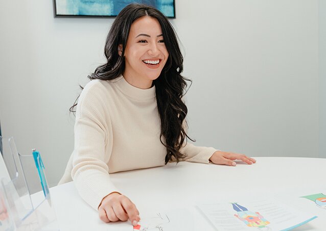 Happy woman in a cream sweater pointing at a map of the major hair growth stages