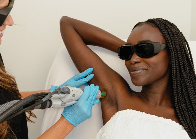 A woman wearing a white towel and protective eyewear gets laser hair removal treatment on her underarms from a Milan Laser Provider in an image for a blog titled Diode vs. Alexandrite vs. Nd:YAG Laser Hair Removal: Key Differences Explained.