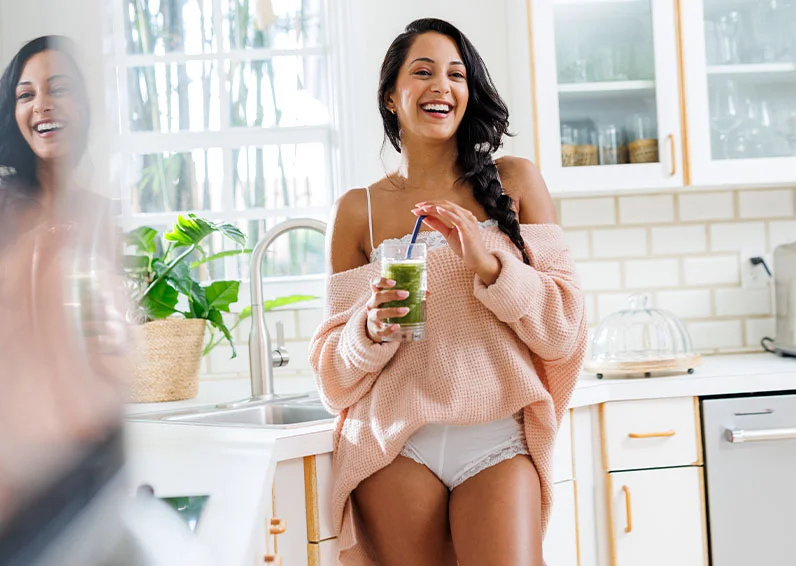 Brunette brimming with confidence after getting leg laser hair removal holding a glass of coffee