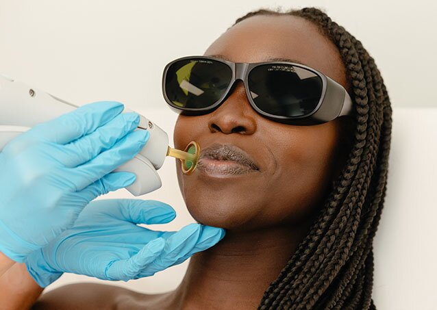 Woman in UV protective glasses getting treatments on her face for a piece on the various types of laser hair removal machines and technologies