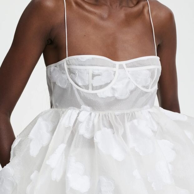 A model wearing a white floral fil-coupé peplum bustier top.