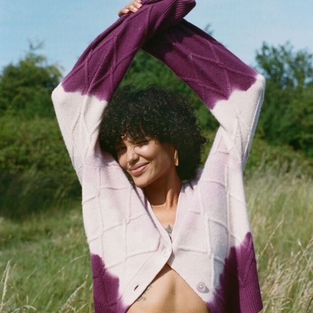 A model wearing a pink to purple ombré dip-dyed cashmere cardigan with a a slouchy silhouette.