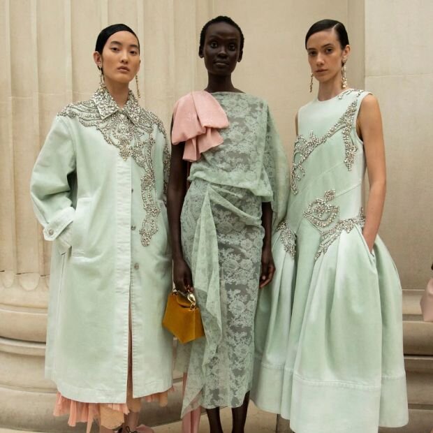 Three women wearing mint-colored dresses and coats with silver details and intere