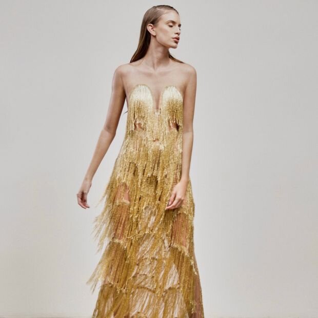 A model wearing a gold draped fringe tulle gown.