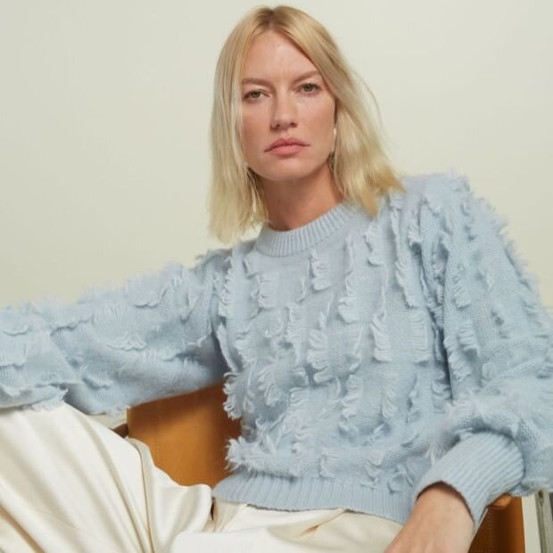 A model wearing a powder blue wool fringe sweater with billowed sleeves and a ribbed crewneck collar.