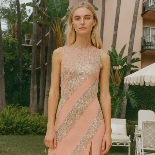 A model wearing a pink satin gown with silver chai