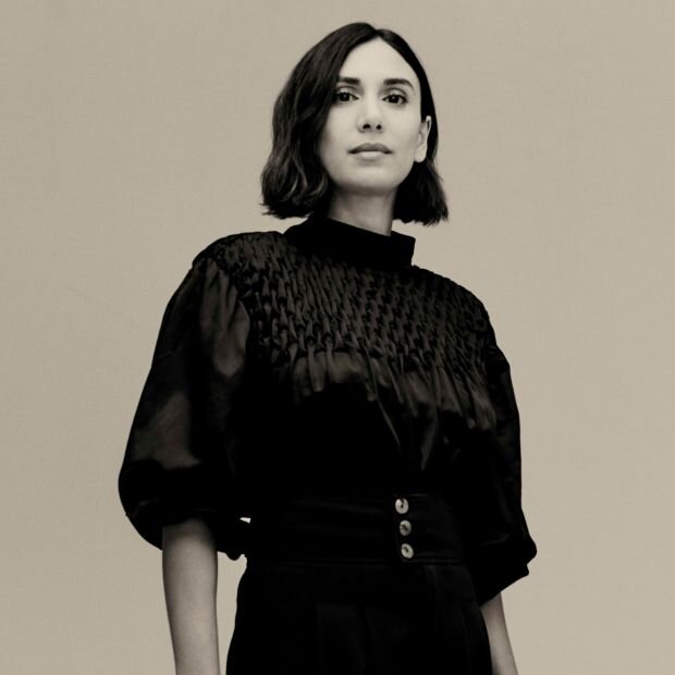 A woman wearing a black smocked top with sheer puff sleeves.