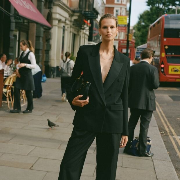 A model wearing a black linen tailored blazer with matching linen trousers.