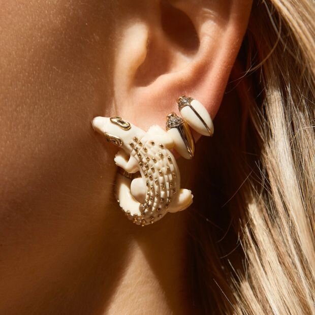 A model wearing a 18-karat white gold earring sculpted in the shape of an alligator with green tsavorites.