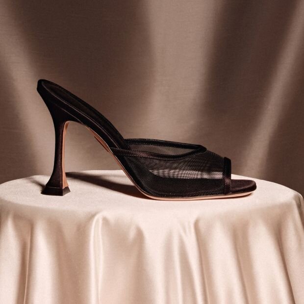 A pair of black heels with a mesh vamp, and dropped kitten heel.