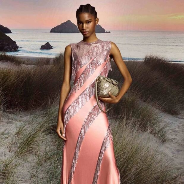 A model wearing a pink satin gown featuring chainmail mesh fringe and a effortless fluid silhouette.