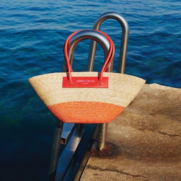 A large size raffia tote with a beach basket aesthetic, featuring a salmon pink leather-trimmed.