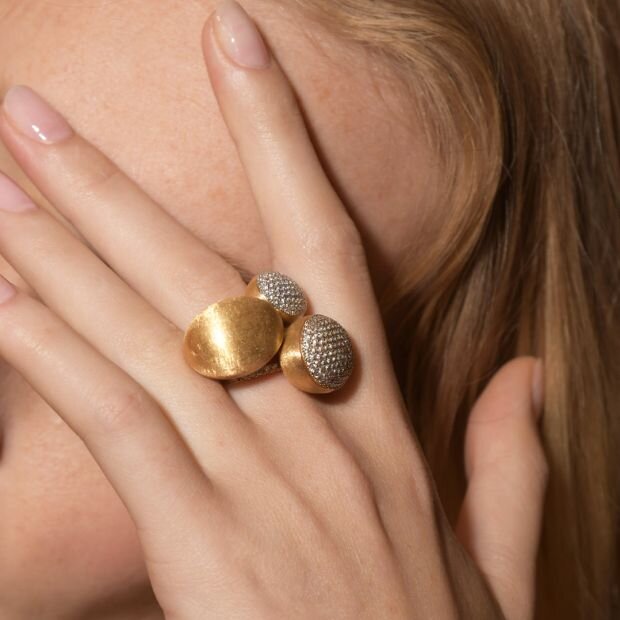 A model wearing gold and diamond rings stacked on top of one another.