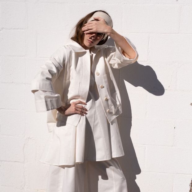 A model wearing a matching tailored white jacket and trousers.